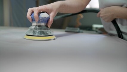 Sanding MDF panels using a machine, furniture production. The process of sanding a wooden panel, female hand. Sanding wood plank.