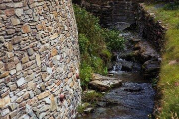 Fototapeta na wymiar water flowing between two stone walls and grass at the edge