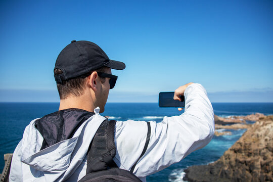 a man takes pictures of nature on his phone. guy takes pictures of the sea