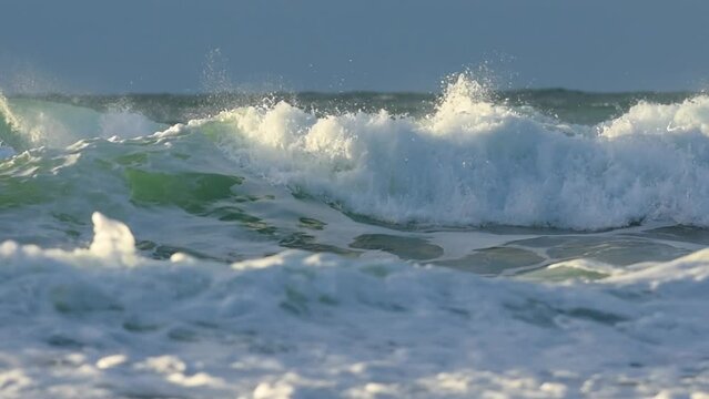 Slow motion video of sea waves crashing on the shore on a  sunny day