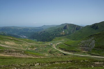 Fototapeta premium Scenic landscape of a winding green valley surrounded by majestic mountains