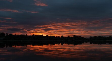 Idyllic landscape featuring a bright sunrise sky over Castle Loch in Scotland