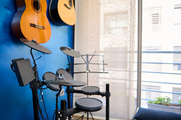 Modern interior of a music studio for home use. Acoustic and electric guitars hanging on blue color...