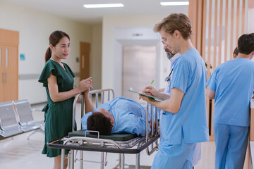 Fototapeta premium Doctors and nurses are waiting to transfer a patient lying on a bed for treatment, with relatives closely watching over him.