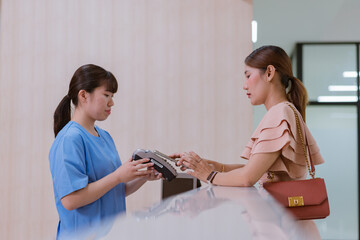 Woman is paying on reception desk in beauty treatment clinic using mobile phone