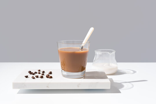 Café con leche en un vaso transparente sobre mármol sobre fondo gris	