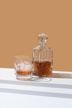 Vasos de whisky con hielo y decantador sobre fondo naranja	