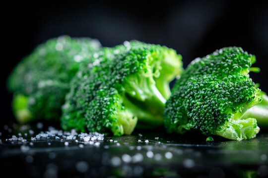 Close-up image of vibrant green broccoli with fresh water droplets on a dark surface