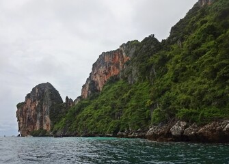 Obraz premium The serene blue sea is complemented by a majestic mountain towering above it, PHI PHI ISLAND, THAILAND 