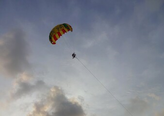 parasailers flying on colourful parachute  in sunset