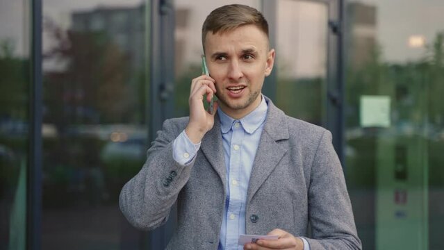 Young businessman talking on the mobile phone, using visit card. Slow motion