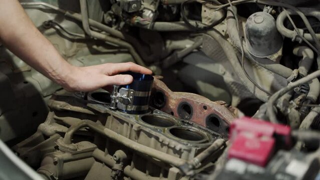 Auto mechanic installs piston using ring compressor into engine block. Professional repairman rebuilds motor, ensures vehicle performance. Hands-on automotive maintenance, precise internal work.