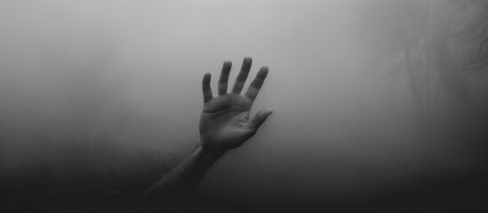a hand is reaching out from behind a glass wall in a black and white photo