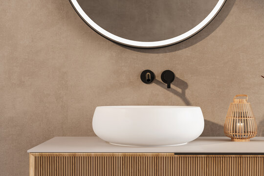 A bathroom sink with a white bowl and a black faucet. The sink is surrounded by a tan wall