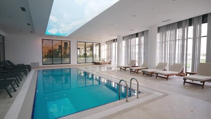 Indoor luxury pool in modern hotel spa with loungers, natural light, serene ambiance. Ideal for leisure, upscale travel,, relaxation.