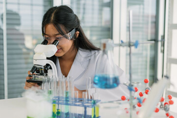 Professional woman scientist conducts research using a microscope among laboratory glassware.