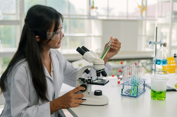 Professional woman scientist conducts research using a microscope among laboratory glassware.