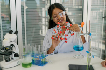 Young scientist studying a molecular structure model in a contemporary laboratory environment.