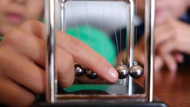 Little boys studying Newton's pendulum at table