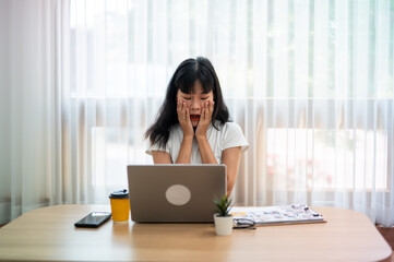 Asian woman looks excited with news received on laptop in bright room