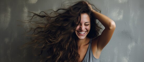 Happy woman with layered hair smiling and holding it in the air - obrazy, fototapety, plakaty