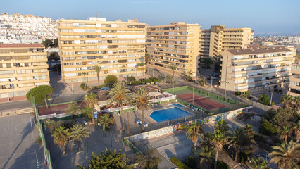 Swimming pool in beautiful morning light surrounded by apartments and palm trees of Cabo Cervera in...