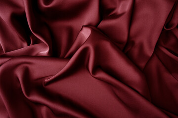 Red silk silky satin fabric. Wavy shiny luxurious shine drapery background, material texture. Full...