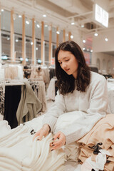 Korean teenage girl choosing and buying trendy clothes in a shopping mall. Retail and consumerism. Sale promotion and shopping concept. Part of a series - 772392971
