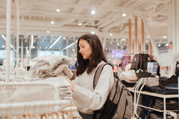Korean teenage girl choosing and buying trendy clothes in a shopping mall. Retail and consumerism. Sale promotion and shopping concept. Part of a series - 772394995