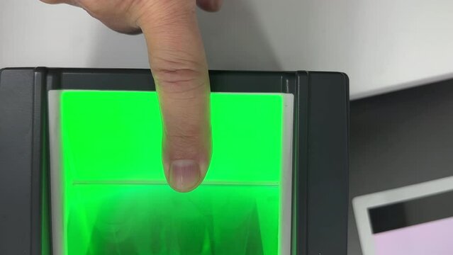 Scanning one finger, index finger fingertip in the office on real digital fingerprint scanner connected via USB to the PC, desktop computer; handheld shot.