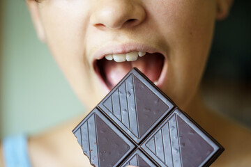 Anonymous teenage girl with mouth wide open eating chocolate bar