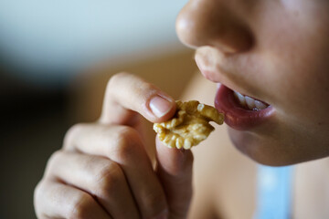 Crop anonymous teenage girl eating healthy walnut kernel