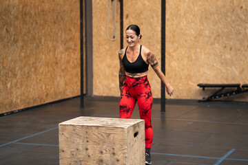 Strong woman about to jump into box in a gym - 772406902