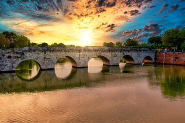 Roman ancient tiberius and augusto bridge over marecchia river in Rimini Italy at sunset or sunsrise