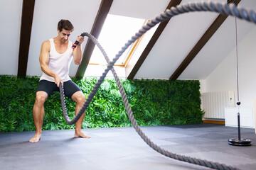 Strong sportsman exercising with battle ropes - 772411153