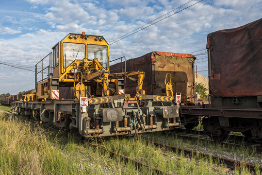 Rail train, Train intended for rail transportation made up of MMQ platforms, machine for laying rails on tracks with blue sky background and freight cars,