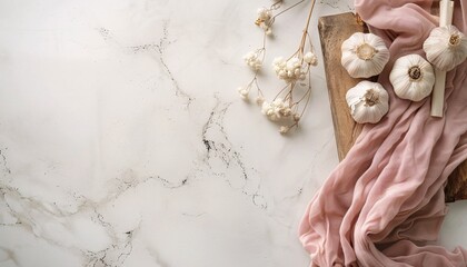 Garlic on a wooden board, a napkin and small white flowers on a light marble background. - obrazy, fototapety, plakaty