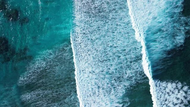 Aerial top drone shot of long tide or swash zone of surf waves crash on the shoreline. Ocean water element power. Caribbean reef. Zoom in. 