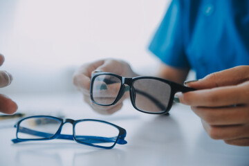 Close-up of Asian female doctor talking with elderly patient showing eyeball model and explaining...