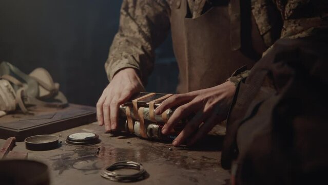 A man builds a bomb in his workshop at night