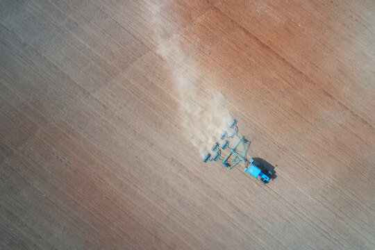 Spring sowing campaign. Tractor with packer rollers cultivates the field before or after sowing seeds. Drone footage.
