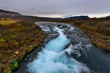 Landscape of Bruarfoss waterfall in Iceland at sunset. Bruarfoss famous natural landmark and tourist destination place. Travel and natural Concept of the Mystery of the blue Waterfall.