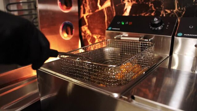 Hand pulling nuggets out of the deep fryer