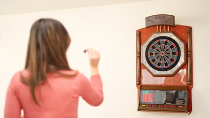 Rear view of a woman playing darts at home