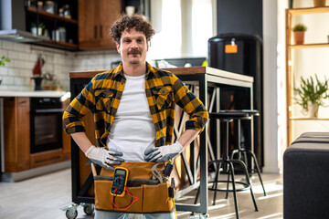 Portrait of Latino handyman. Standing in the kitchen with all the equipment.