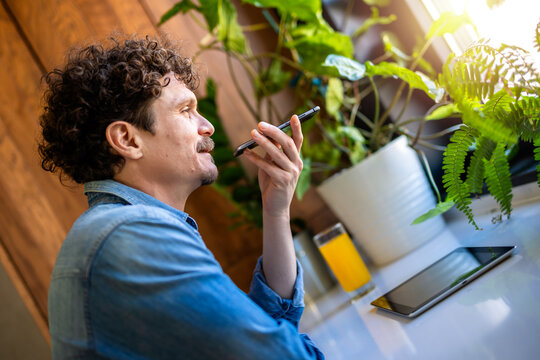 Latino man sending a voice message on his phone.