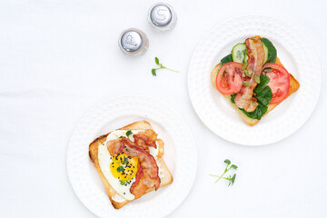  Sandwiches with fried eggs, fried ham, tomatoes, cucumbers, pepper on white background, top view.
