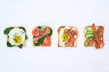  Sandwiches with fried eggs, fried ham, tomatoes, cucumbers, pepper on white background, top view.