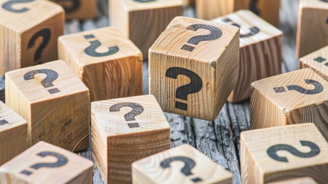 Collection of wooden cubes with black question marks on a rustic wooden background. Conceptual image for quiz, FAQ, and mystery games