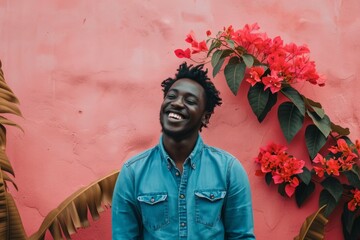 Joyful man smiling with a vibrant pink wall and red flowers in the background.